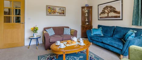 A living room with a brown sofa, a blue sofa, a wooden coffee table, and a patterned rug.