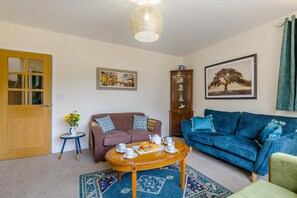 Ein Wohnzimmer mit einem braunen Sofa, einem blauen Sofa, einem Holztisch und einem gemusterten Teppich.