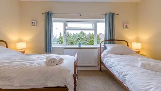 A hotel room with two single beds, a window with curtains, a radiator, and bedside lamps. - 2 Bed in Heacham (oc-l44862) (Heacham)