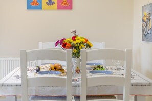A dining table set with plates, a vase of flowers, and a bottle of mustard. - 2 Bed in Heacham (oc-l44862) (Heacham)