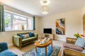 Ein Wohnzimmer mit einer Couch, einem Couchtisch, einem Fernseher und einem Gemälde an der Wand.