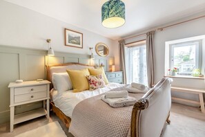 A bedroom with a bed, bedside tables, a mirror, a window with curtains, and a view of the outdoors. - 2 Bed in Marldon (oc-k41049) (Marldon)