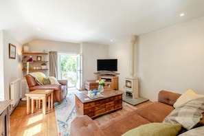 Ein Wohnzimmer mit Kamin, Ledersofas, einem Couchtisch und einem Fernseher.