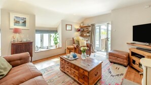 A living room with a sofa, a coffee table, a television, and a sliding glass door leading to a balcony. - 2 Bed in Marldon (oc-k41049) (Marldon)