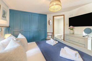 Ein Hotelzimmer mit einem großen Bett, einem blauen Kleiderschrank, einem Badezimmer mit Spiegel und einer Pendelleuchte.