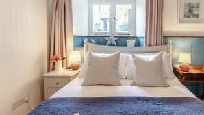 A bedroom with a bed, two bedside tables, a window with curtains, a star decoration, and a wall-mounted picture. - 2 Bed in Marldon (oc-k41049) (Marldon)