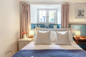 Ein Schlafzimmer mit einem Bett, zwei Nachttischen, einem Fenster mit Vorhängen, einer Stern-Dekoration und einem Wandbild.