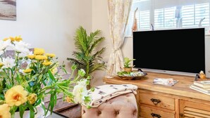 A room with a wooden desk, a television, a window with curtains, and various plants. - 2 Bed in Westleton (oc-w42586) (Westleton)