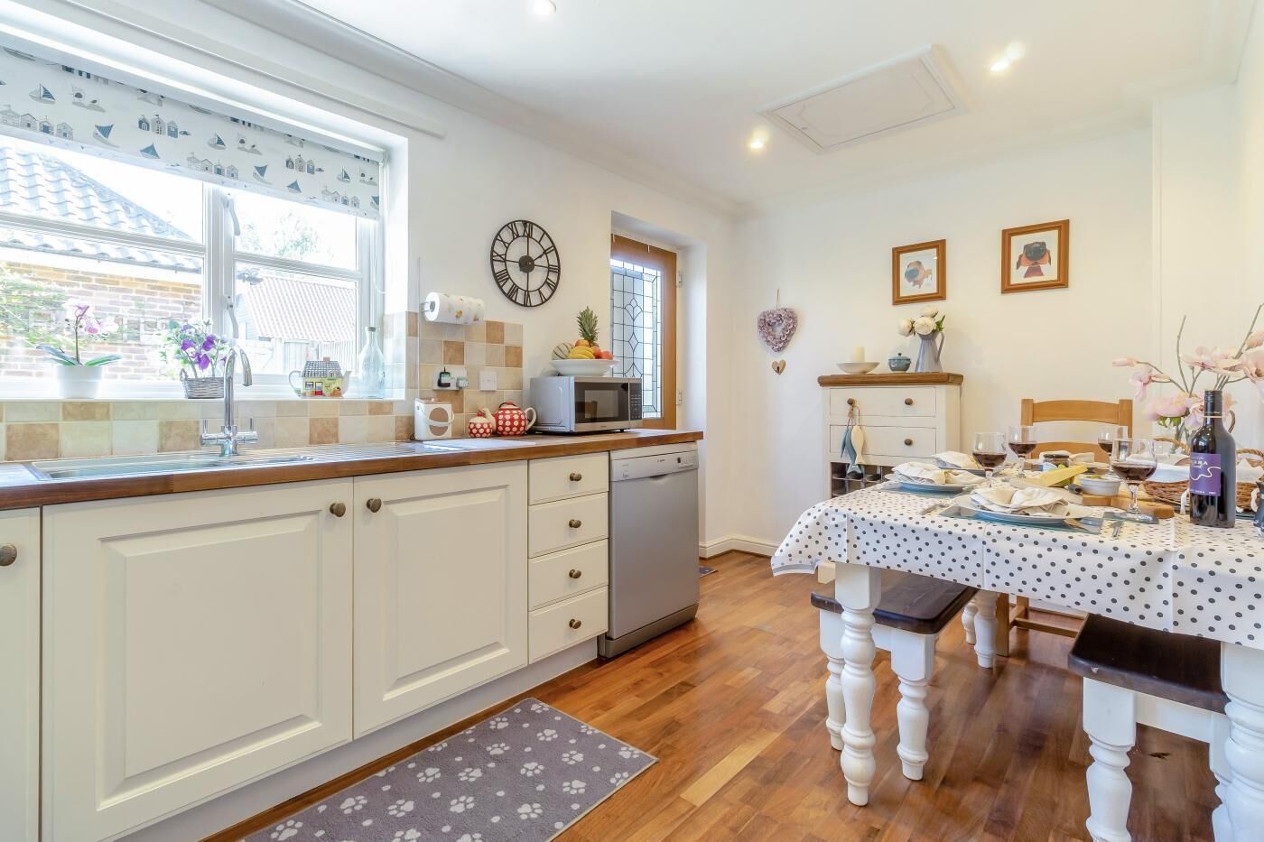 A kitchen with white cabinets, a microwave, and a dining table set for two.