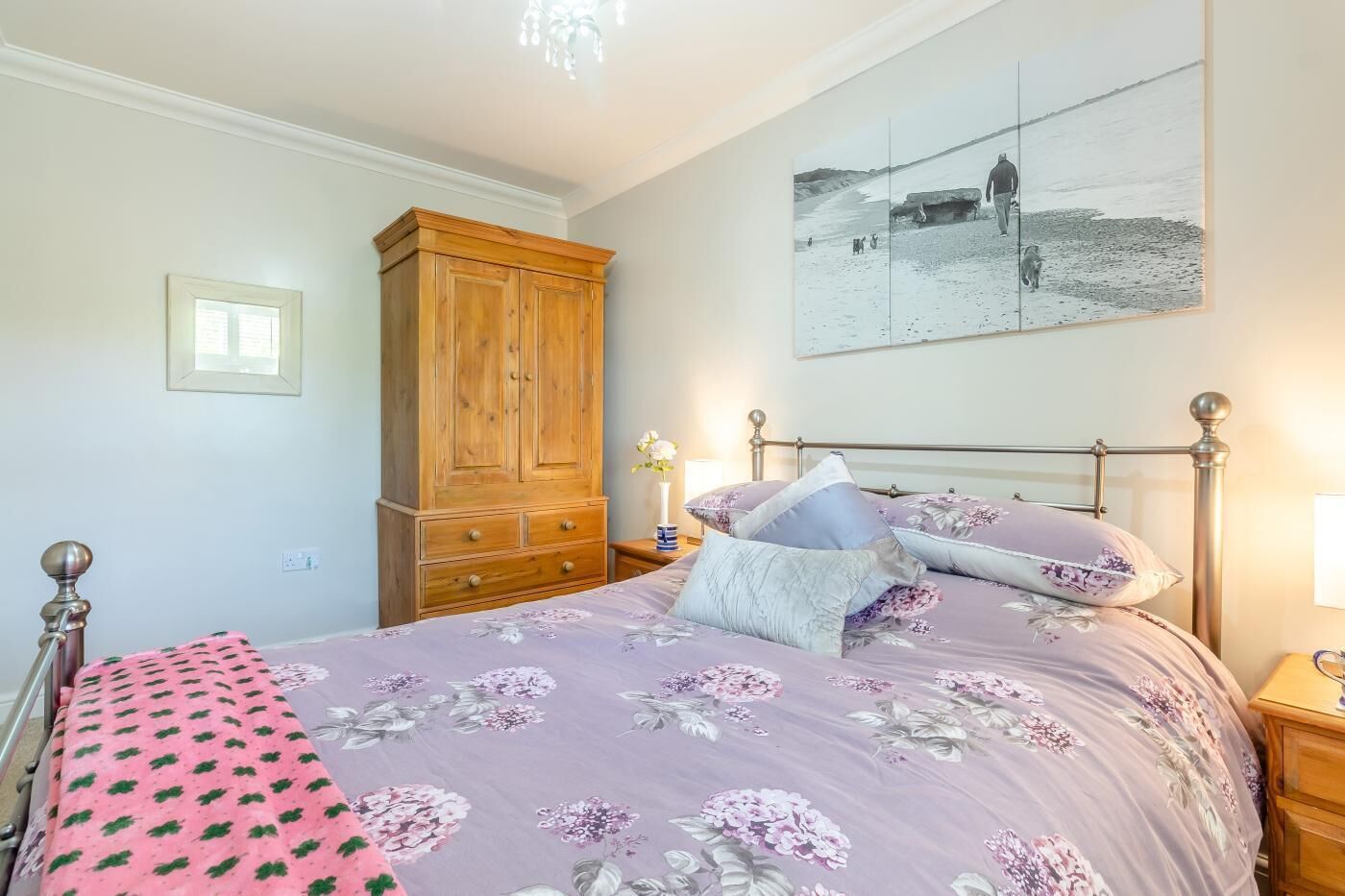 Une chambre à coucher avec un lit, une armoire en bois et un tableau accroché au mur.