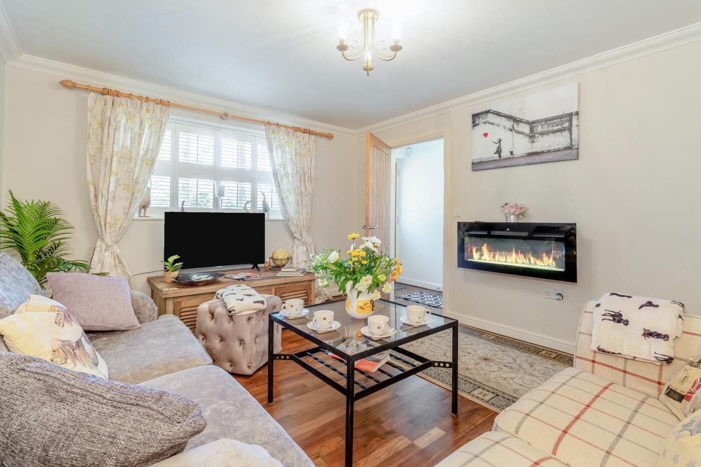 A living room with a sofa, armchair, coffee table, television, fireplace, and decorative items.