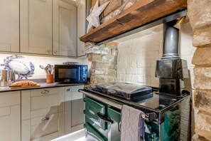 Eine Küche mit Steinwand, einer Mikrowelle, einem Toaster und einem grünen Backofen.