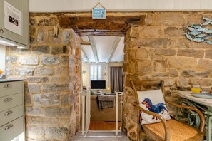A stone-walled room with a bed, a chair, and a table with a glass of orange juice. - 3 Bed in Robin Hoods Bay, Whitby (oc-g43284) (Robin Hood's Bay)