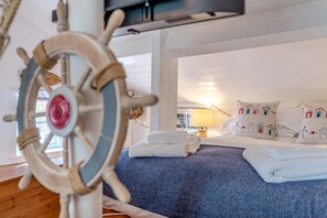 A bedroom with a bed, pillows, a headboard, and a ship's wheel. - 3 Bed in Robin Hoods Bay, Whitby (oc-g43284) (Robin Hood's Bay)