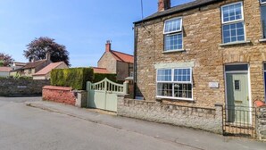 A stone building with a green gate, a brick wall, and a clear sky. - 3 Bed in Waddington (oc-c45566) (Waddington)