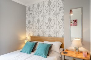 Et hotelværelse med seng, et natbord, en lampe og et spejl.