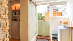 A kitchen with a stone wall, a green door, and a window with a view of the outside. - 3 Bed in Waddington (oc-c45566) (Waddington)