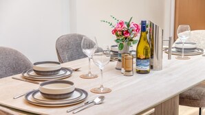Een eettafel gedekt met borden, bestek, glazen en een fles wijn.