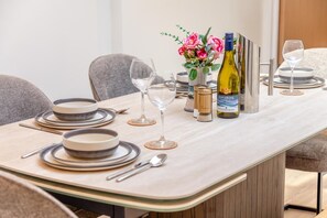 A dining table set with plates, cutlery, glasses, and a bottle of wine. - 4 Bed in Bolingey (oc-m45595) (Bolingey)