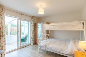 A bunk bed room with a ladder, a table with a lamp, and a sliding glass door leading to an outdoor area. - 4 Bed in Bolingey (oc-m45595) (Bolingey)