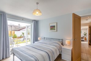 A bedroom with a bed, bedside tables, a window, and an open door leading to a bathroom. - 4 Bed in Bolingey (oc-m45595) (Bolingey)
