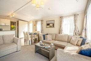 A modern living room with a sofa, coffee table, and dining area. - 3 Bed in Abersoch (oc-a45542) (Abersoch)