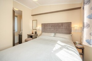 Ein Hotelzimmer mit einem großen Bett, Nachttischen, einem Spiegel und einem Fenster mit Jalousien.