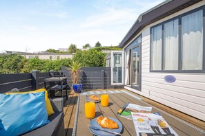 A deck with outdoor seating, a table with breakfast items, and a potted plant.