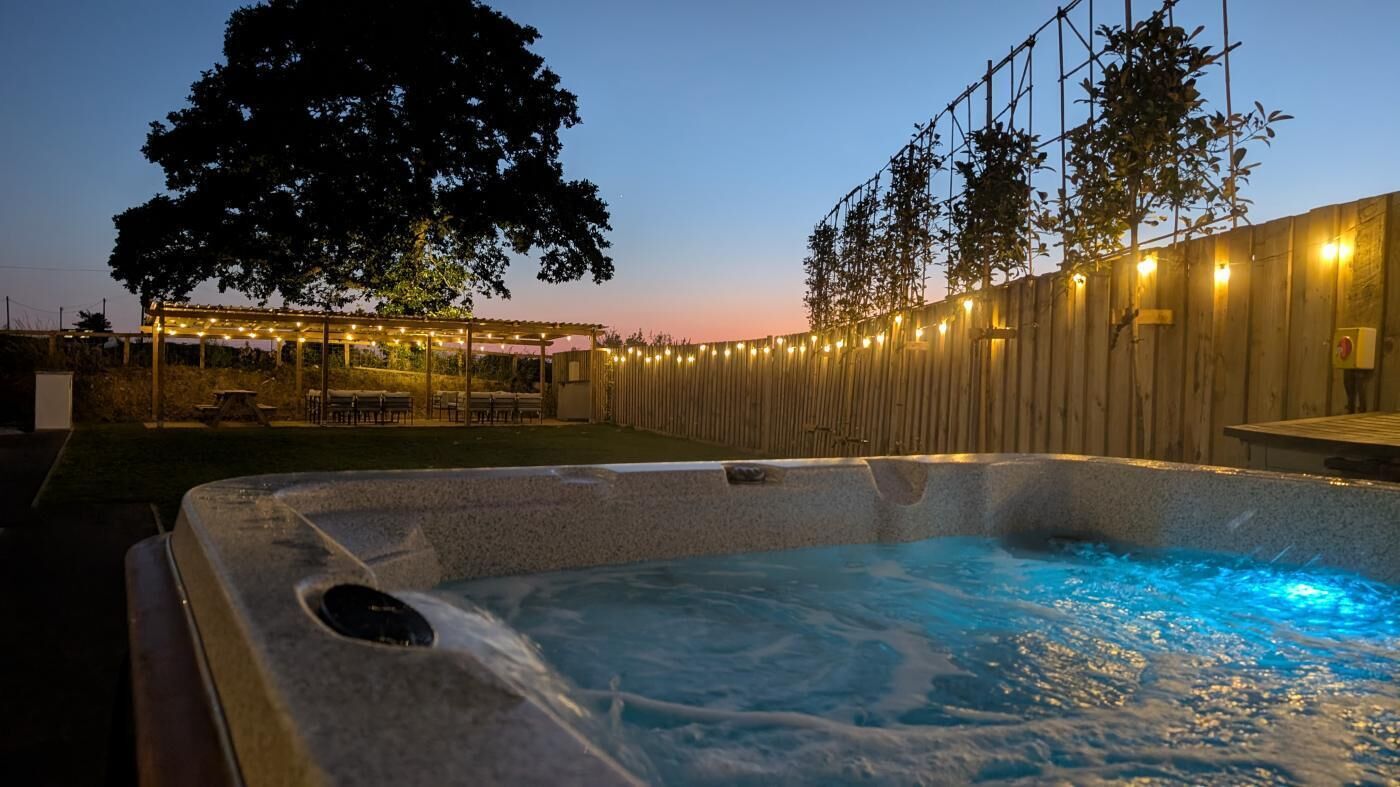 Ein Whirlpool mit Holzzaun und Lichterkette im Hintergrund.