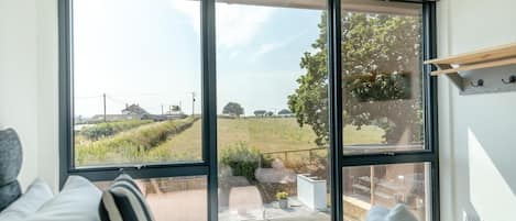 A bedroom with a large window, a bed, and a view of a rural landscape.