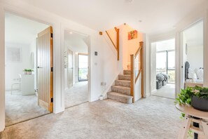 A modern interior with a carpeted floor, a wooden staircase, and a view through a glass door. - 7 Bed in Broadwoodkelly (oc-b45447) (Broadwood Kelly)