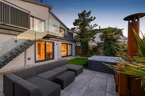 Ein modernes Haus mit Wendeltreppe aus Glas, einer Terrasse mit Sofa und einem Whirlpool.