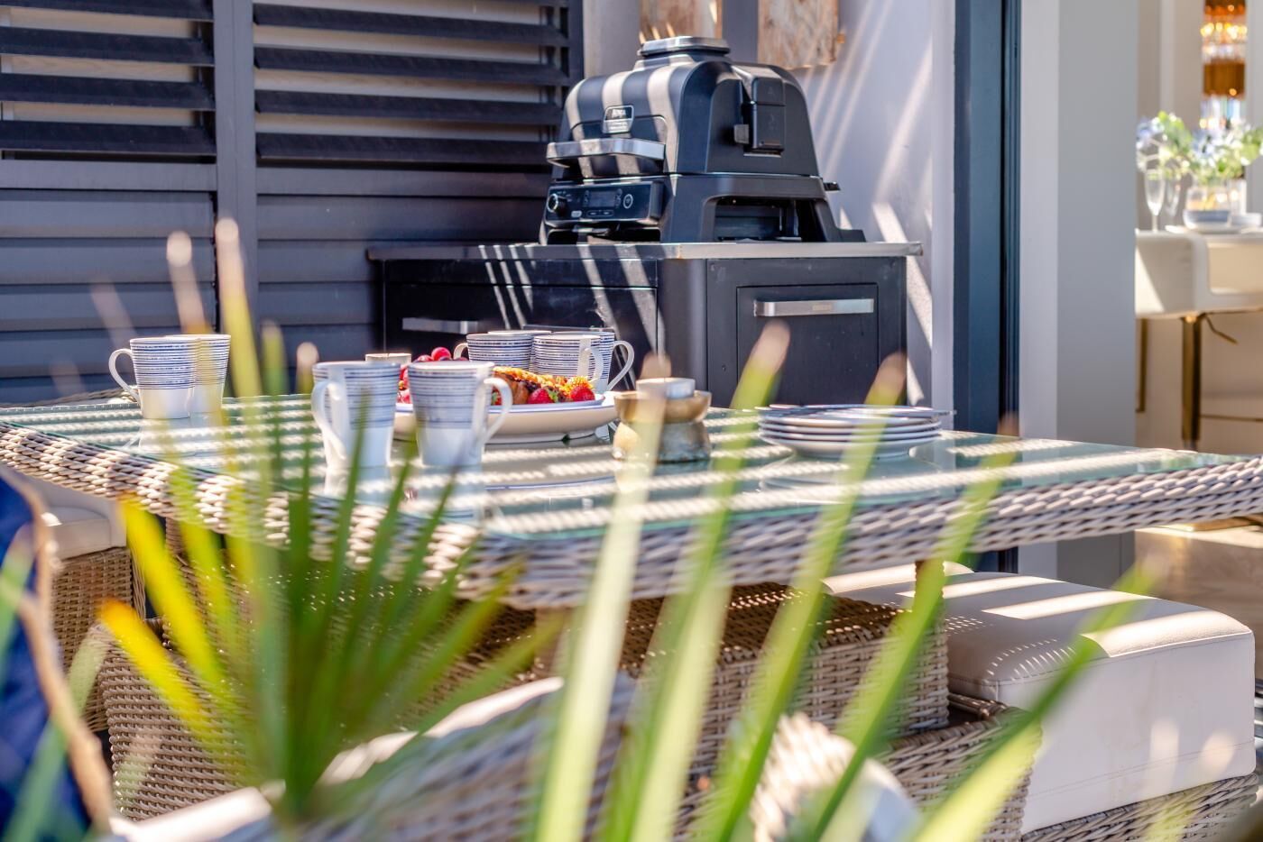 An outdoor dining area with a round table, chairs, and a grill.