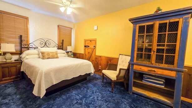 A bedroom with a bed, a nightstand, a dresser, a chair, and a window with a view.