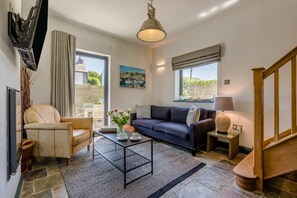 Ein Wohnzimmer mit Sofa, Sessel, Couchtisch und einem Bild an der Wand.