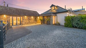 A residential property with a gravel driveway, stone walls, and a well-lit entrance. - 5 Bed in Windmill (oc-o45436) (Trevone)