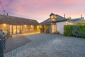 Ein Wohnhaus mit Kiesauffahrt, Steinmauern und einem gut beleuchteten Eingang.