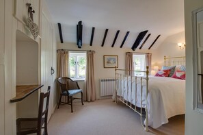 A bedroom with a bed, a chair, a radiator, and a window. - 2 Bed in Castle Acre (oc-r18323) (Castle Acre)