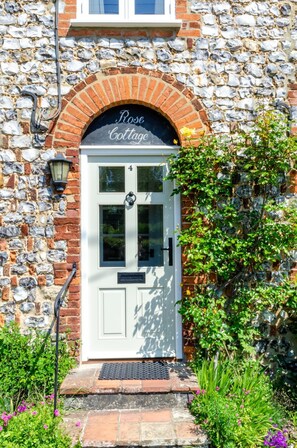 A stone building with a white door labeled 'Rose Cottage.' - 2 Bed in Castle Acre (oc-r18323) (Castle Acre)
