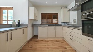 Eine moderne Küche mit weißen Schränken, Holzboden und Edelstahlgeräten.