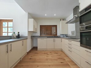 Eine moderne Küche mit weißen Schränken, Holzboden und Edelstahlgeräten.