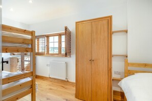 A room with bunk beds, a wooden wardrobe, a window with blinds, and a radiator. - 3 Bed in Marshwood (oc-w34352) (Marshwood)