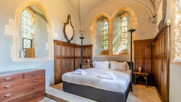 A bedroom with a large bed, wooden wardrobe, and arched windows. - 2 Bed in Market Stainton (oc-s45536) (Market Stainton)