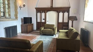 A room with a television, two sofas, a radiator, and a wooden door. - 2 Bed in Market Stainton (oc-s45536) (Market Stainton)