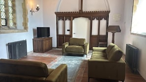 A room with a television, two sofas, a radiator, and a wooden door. - 2 Bed in Market Stainton (oc-s45536) (Market Stainton)