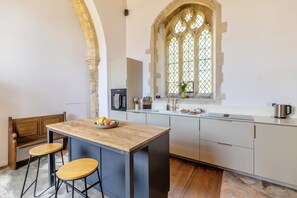 A kitchen with a central island, bar stools, a stone arch, and a large window with a view. - 2 Bed in Market Stainton (oc-s45536) (Market Stainton)