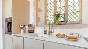 A modern kitchen with a glass countertop, a gold faucet, and a window with a view. - 2 Bed in Market Stainton (oc-s45536) (Market Stainton)
