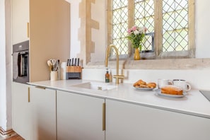 A modern kitchen with a glass countertop, a gold faucet, and a window with a view. - 2 Bed in Market Stainton (oc-s45536) (Market Stainton)