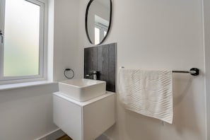 A bathroom with a white sink, a mirror, a towel rack, and a window. - 1 Bed in Chacewater (oc-l45269) (Chacewater)