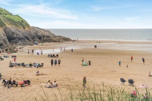 A beach with people, tents, and beach chairs.
